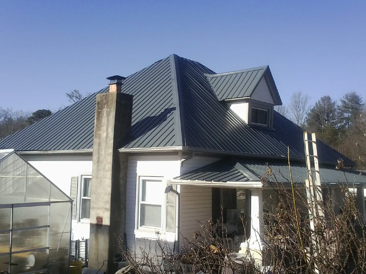 Dark blue standing seam metal roof on a white farmhouse with dormer — Slate & Tile Roof Repair by Roofing Brothers in Joppa