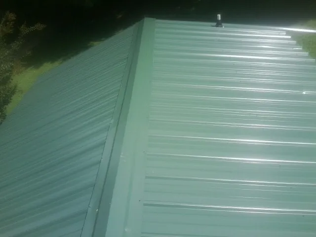 New green metal panels meeting at the ridge of a roof — Flat Roof Repair work by our crew in Joppa