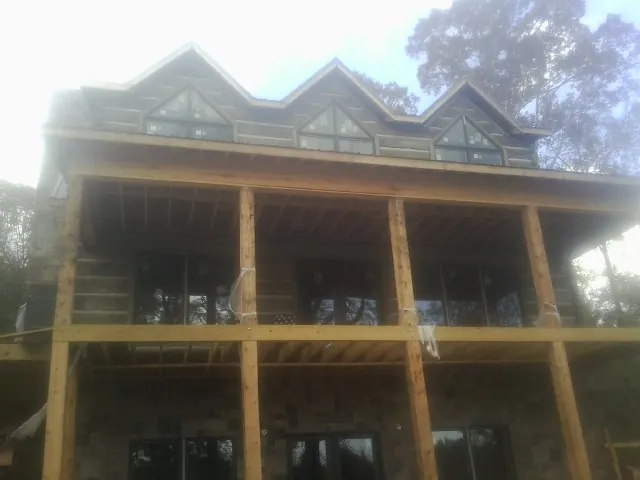 Dormers and porch framing on a large log home under construction — Roof Coating work by our crew in Joppa